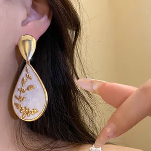 Close-up detail of a vintage water drop pendant earring featuring an elegant gold floral pattern