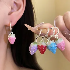 Vibrant colorful enamel strawberry dangle earrings with silver needles shown on model