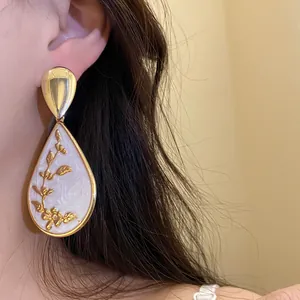Close-up detail of vintage style gold floral teardrop earring worn on a model's ear