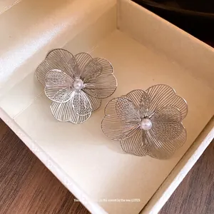 Élégantes boucles d'oreilles fleurs en métal avec perle dans une boîte cadeau luxe