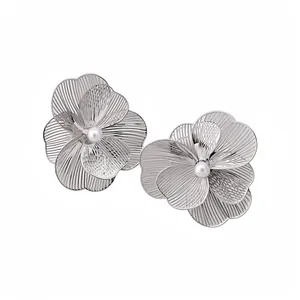 Élégantes boucles d'oreilles fleurs en métal argenté avec perles sur fond blanc