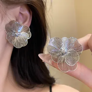 Vue détaillée d'élégantes boucles d'oreilles fleurs en fil d'argent avec perle centrale