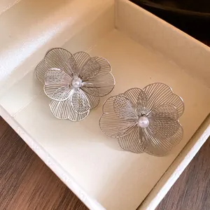 Vue détaillée d'élégantes boucles d'oreilles fleur en métal argenté avec perle centrale