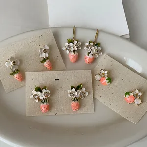Close-up detail of sweet 18k gold plated strawberry and white flower stud earrings set