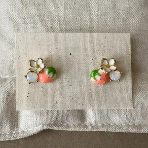Detail view of 18k gold plated strawberry and flower stud earrings with silver needles