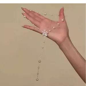 Detailed view of elegant pearl flower adjustable lariat necklace held in hand on beige backdrop