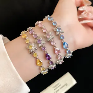 Gros plan de bracelets élégants en zircon avec motifs de fleurs et de gouttes au poignet.
