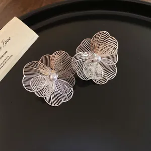 Vue macro d'élégantes boucles d'oreilles fleurs en fil d'argent avec perles sur noir