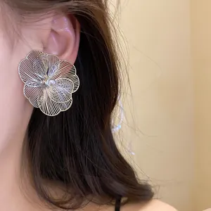 Gros plan détaillé d'une grande boucle d'oreille fleur métallique avec perle centrale