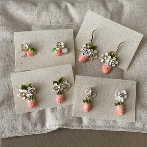 Detail view of 18k gold plated strawberry and flower earrings with crystals