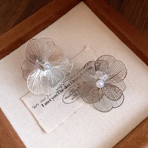 Vue détaillée des boucles d'oreilles clips fleurs en métal avec pétales fins et perle centrale.