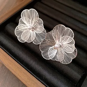 Elegant metal filigree flower earrings with central pearl in luxury jewelry box