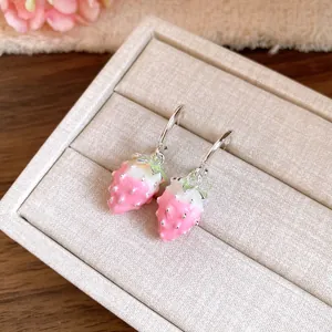 Detailed view of pink enamel strawberry dangle earrings in a jewelry box