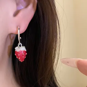 Close-up of sweet oil-drop strawberry pendant earrings with silver needle on ear