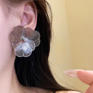 Elegant oversized silver wireframe flower earrings with pearl center on model