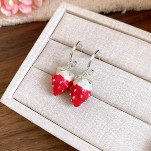 Close-up of sweet strawberry pendant earrings on a beige jewelry box