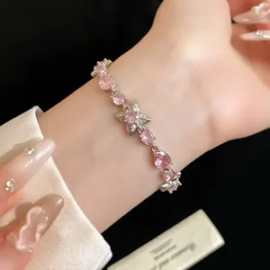 Gros plan d'un bracelet élégant en argent avec des fleurs en zircon rose porté au poignet.