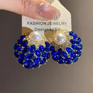 Primer plano detallado de pendientes vintage con perlas y pedrería azul en tarjeta