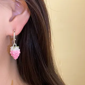 Detailed close-up showing a cute pink enamel strawberry pendant earring worn on an ear