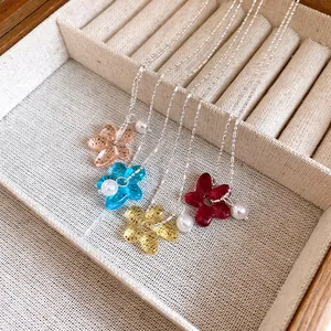 Gros plan de pendentifs fleurs translucides colorés et de perles sur chaînes à boules argentées