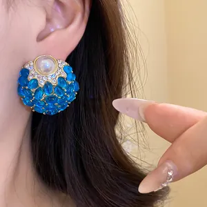 Primer plano de pendientes vintage de perlas redondas con piedras azules y cristales