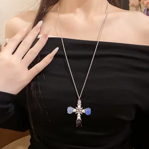 Detail of elegant cross pendant necklace with pearls and blue resin stones on model