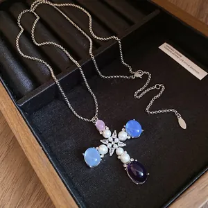 Detail view of a zircon pearl and resin cross pendant necklace in a jewelry tray