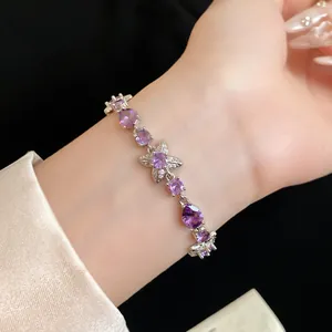 Détail d'un bracelet en argent avec fleurs en zircon violet et breloques cœur