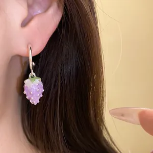 Close-up detail of a charming purple enamel strawberry drop earring on a silver hoop