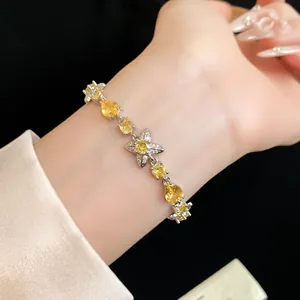 Gros plan d'un bracelet en argent avec des zircons jaunes en forme de fleur et goutte