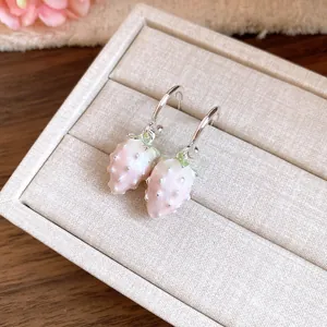 Detailed close-up of cute pink drip oil strawberry pendant earrings on a jewelry box.