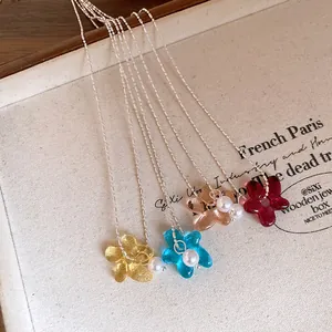Gros plan de pendentifs fleurs en résine colorée avec de petites perles sur chaînes argent.
