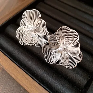 Macro view of elegant silver filigree flower earrings with central white pearl accents.
