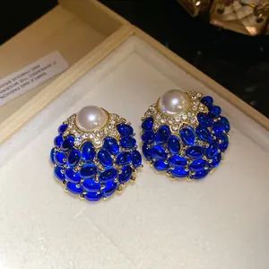 Primer plano de pendientes vintage dorados con piedras azules, cristales y perla