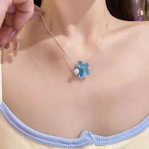 Gros plan d'un collier fleur en verre bleu avec pendentif perle sur chaîne argent
