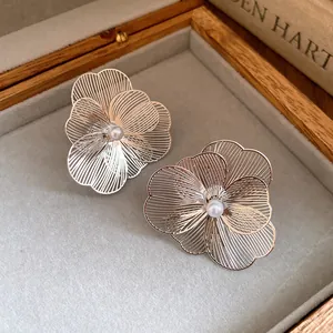 Macro view of elegant silver hollow flower earrings with delicate central pearl details.