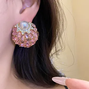 Detalle de pendientes vintage con piedras rosas y una perla blanca central muy elegante