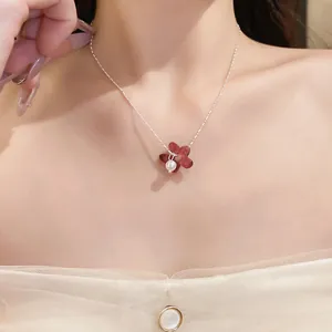 Détail d'un collier avec pendentif fleur rouge et perle blanche sur un mannequin
