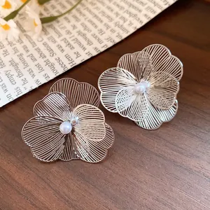 Detailed view of silver hollow metal flower earrings featuring a central white pearl