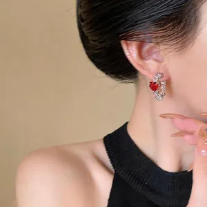 Detail view of C-shaped earring featuring a red heart zircon and pink crystals