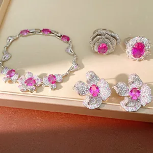 Makroansicht des rosa Blumen-Schmucksets mit Armband Ohrringen und Ringen auf einem Display-Tablett