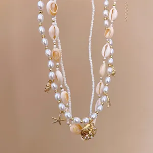 Detail view of layered waist chain with pearls, shells, and starfish charms in gold tone.
