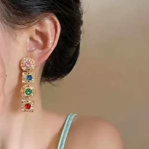 Vintage style geometric earrings with colorful crystals worn by a model in warm light