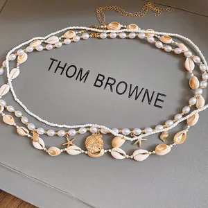 Detail view of beach style pearl and shell beaded waist chain with gold starfish charms