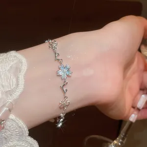 Dettaglio ravvicinato di un elegante bracciale in argento a fiori di ciliegio con zirconi blu
