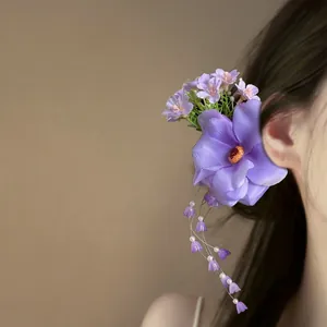 Detail showing a purple flower hair clip with delicate pearl and floral tassels.