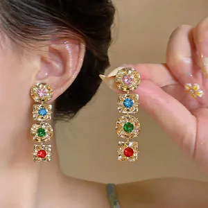 Close-up of vintage geometric earrings with multi-colored rhinestones and gold finish