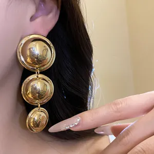 High-quality close-up showing vintage gold metallic triple round dangle earrings on a model's ear
