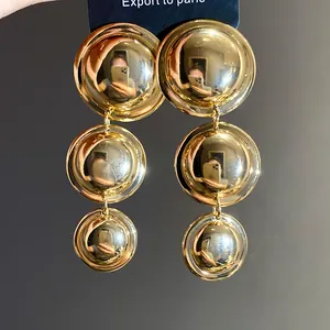 Detail view of vintage gold polished triple-drop round earrings on blue display card