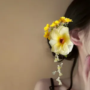 Close-up detail of a yellow floral hair clip with delicate beaded flower tassels